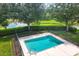 Aerial view of a community pool surrounded by a black metal fence and lush landscaping with a lake view at 3125 57Th Avenue E Cir, Bradenton, FL 34203