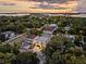 Stunning aerial view of a modern home nestled among lush greenery, with a beautiful sunset backdrop at 3464 Camino Real, Sarasota, FL 34239