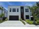 Modern two-story home with a black garage door, clean lines, and well-manicured landscaping at 3464 Camino Real, Sarasota, FL 34239