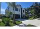 Striking modern home with a black garage door and lush landscaping, set against a blue sky at 3464 Camino Real, Sarasota, FL 34239