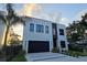 Contemporary two-story home featuring a black garage door, modern windows, and minimalist landscaping at 3464 Camino Real, Sarasota, FL 34239