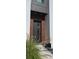 Modern front door with wood slat accent, stylish lighting, and manicured landscaping at 3464 Camino Real, Sarasota, FL 34239