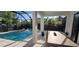 Enclosed patio with a swimming pool, hot tub, dining table, and comfortable seating at 3464 Camino Real, Sarasota, FL 34239