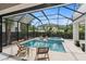 Enclosed swimming pool with lounge chairs, spa, lush landscaping, and a screened enclosure at 3464 Camino Real, Sarasota, FL 34239