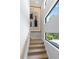 Bright staircase featuring hardwood steps, white walls, modern windows, and stylish lighting at 3464 Camino Real, Sarasota, FL 34239