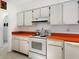 Retro kitchen with orange countertops and white cabinets at 302 Mendez Dr, Sarasota, FL 34243