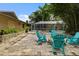 Brick patio with teal chairs and fire pit, adjacent to the house and screened enclosure at 1525 17Th W St, Palmetto, FL 34221