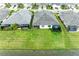 Aerial view of houses with gray roofs, lanais, and a green lawn by the lake at 2942 Trustee Ave, Sarasota, FL 34243