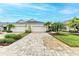 Two-car garage, paver driveway, and landscaped yard with palm trees at 2942 Trustee Ave, Sarasota, FL 34243