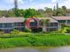 Condominium exterior featuring screened balconies and verdant landscaping along the waterfront at 1520 Pelican Point Dr # 251, Sarasota, FL 34231