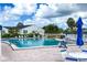 Community pool with lounge chairs and patio tables under blue umbrellas at 4819 Independence Dr # 4819, Bradenton, FL 34210