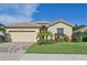Tan house with a two-car garage and lush landscaping at 1480 Mossy Oak Dr, North Port, FL 34287