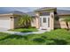 Front view of a tan house with a white door, palm trees and a walkway at 13592 Clara Ln, Port Charlotte, FL 33981