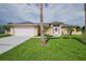 Tan house with a white door, two-car garage and palm trees at 13592 Clara Ln, Port Charlotte, FL 33981