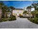 An eye-level exterior view of a modern-designed home, surrounded by palm trees and lush greenery at 7665 Sanderling Rd, Sarasota, FL 34242