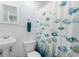 Bathroom with coastal theme; featuring a pedestal sink, toilet, and a shower with a decorative fish curtain at 5307 2Nd Avenue Nw Dr, Bradenton, FL 34209