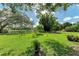 Expansive grassy backyard with mature trees and a tranquil pond view at 907 136Th E St, Bradenton, FL 34212