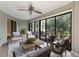 This staged lanai offers seating, a ceiling fan, and floor to ceiling windows looking out to lush landscaping at 3601 Quail Hollow Ln, Bradenton, FL 34210