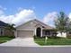 Tan house with a two-car garage and manicured lawn at 1822 Raven Glen Dr, Ruskin, FL 33570
