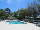 A community pool is shown on a sunny day, surrounded by ample seating and lush greenery at 4939 Lakescene Pl, Sarasota, FL 34243