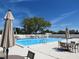 Sparkling community swimming pool with ample seating, umbrellas and a blue sky backdrop at 4939 Lakescene Pl, Sarasota, FL 34243