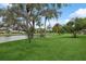 Landscaped backyard with lush grass, mature trees, and a serene lake view at 3973 Boca Pointe Dr, Sarasota, FL 34238