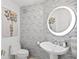 Stylish half bath with decorative butterfly art, unique round lighted mirror, vessel sink, and modern tiled walls at 128 Golden Gate Pt # 501B, Sarasota, FL 34236
