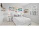 Bright bedroom with white bedding, beach art, bedside tables, and a window with plantation shutters at 128 Golden Gate Pt # 501B, Sarasota, FL 34236