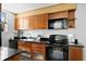 Galley kitchen featuring stainless steel appliances, wooden cabinets, and black countertop at 128 Golden Gate Pt # 501B, Sarasota, FL 34236