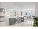Open kitchen and living area boasts modern gray cabinets, a wine cooler, marble tile and island seating at 128 Golden Gate Pt # 501B, Sarasota, FL 34236