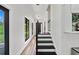 Light-filled hallway featuring black-and-white stairs and modern-style black frame windows at 13331 Drysdale Ave, Port Charlotte, FL 33981