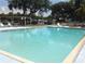 A clear swimming pool with a shallow end surrounded by lounge chairs and tables at 3333 26Th E Ave # 1230, Bradenton, FL 34208
