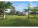 Spacious backyard with lush lawn, palm trees, and a screened patio at 3556 E Forest Lake Dr, Sarasota, FL 34232