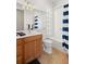 Bathroom with a tub shower, wood cabinets, and blue striped shower curtain at 13180 Ipolita St, Venice, FL 34293