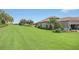 Expansive lawn surrounds home with verdant landscaping, well-maintained grounds, and golf course views at 4507 Terrazza Ct, Bradenton, FL 34211