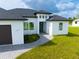 White house with dark gray roof, paved walkway, and landscaped lawn at 1094 Rotonda Cir, Rotonda West, FL 33947