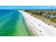 Picturesque aerial view of a long beach with white sand, clear turquoise waters, and scattered beachgoers at 136 Crescent Dr, Anna Maria, FL 34216
