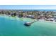 Scenic aerial view of a pier extending into clear blue water, surrounded by coastal homes and a sandy beach at 136 Crescent Dr, Anna Maria, FL 34216
