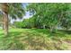 Expansive backyard with lush green grass, mature trees, and yellow kayak on the lawn at 136 Crescent Dr, Anna Maria, FL 34216