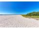 Quiet beach scene with clear skies, calm water, and soft sand, bordered by dune vegetation, ideal for a peaceful day at 136 Crescent Dr, Anna Maria, FL 34216