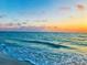 Waves gently lap the shore as the sun sets over the tranquil beach at dusk at 136 Crescent Dr, Anna Maria, FL 34216