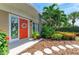 Inviting front entrance with a bright orange door, decorative wreath, and stained-glass window at 136 Crescent Dr, Anna Maria, FL 34216