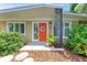 Inviting front entrance with a bright orange door, decorative wreath, and colorful stained-glass window at 136 Crescent Dr, Anna Maria, FL 34216