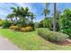 Lush front yard featuring mature palms and tropical foliage enhancing the home's curb appeal at 136 Crescent Dr, Anna Maria, FL 34216