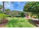 Well-maintained front yard with lush landscaping, a manicured lawn, and an inviting outdoor seating area at 136 Crescent Dr, Anna Maria, FL 34216