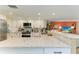 Bright kitchen with white cabinetry, stone countertops, modern appliances, and breakfast bar overlooking living area at 136 Crescent Dr, Anna Maria, FL 34216