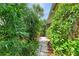 A landscaped path is shown with lush greenery and stone pavers leading around the side of the home at 136 Crescent Dr, Anna Maria, FL 34216