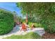 A charming outdoor patio features Adirondack chairs, stone pavers, and lush tropical landscaping at 136 Crescent Dr, Anna Maria, FL 34216