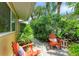 A cozy patio area is featured with two orange Adirondack chairs and lush tropical landscaping at 136 Crescent Dr, Anna Maria, FL 34216