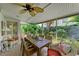 Screened-in porch with a ceiling fan, tropical plants, and a comfortable seating area at 136 Crescent Dr, Anna Maria, FL 34216